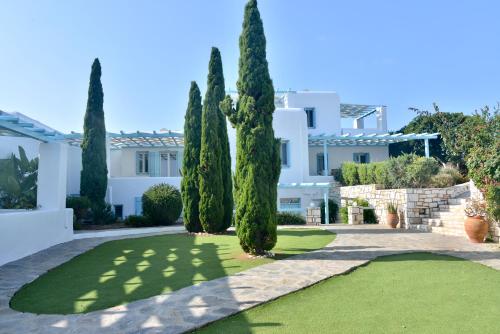 a row of cypress trees in front of a house at Blue Mare Villas in Naousa