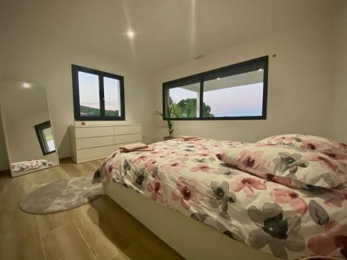 - une chambre avec un lit avec une couette à fleurs et 2 fenêtres dans l'établissement Villa de luxe entre mer et montagne, à Villetelle
