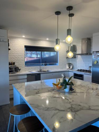a kitchen with a large island with a tv on the wall at Beach house with a pool in Waihi Beach