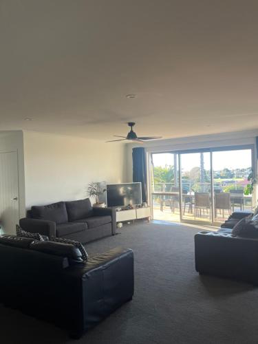 a living room with two couches and a tv at Beach house with a pool in Waihi Beach