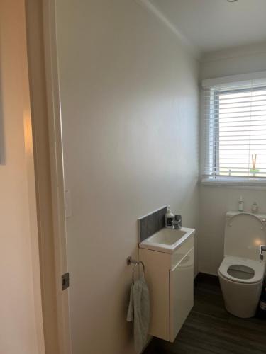 a bathroom with a toilet and a sink at Beach house with a pool in Waihi Beach