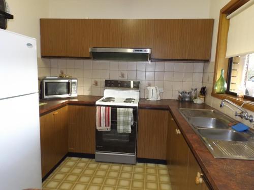 a kitchen with a stove and a sink at Kirazz Holiday Homes in Kingscote