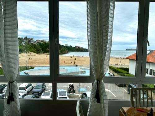 a window with a view of a beach and the ocean at Suances primera línea de playa in Suances