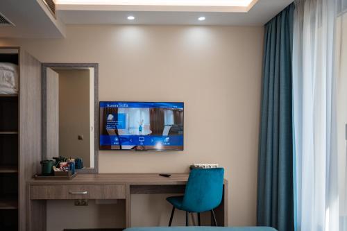 a room with a desk with a blue chair and a television at Aurora Sofia in Sofia