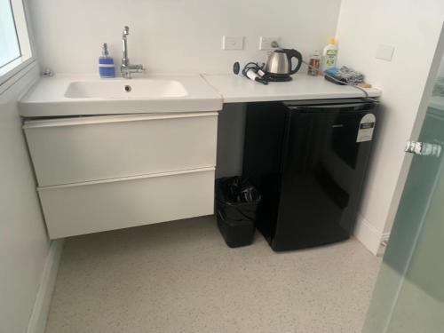 a white kitchen with a sink and a refrigerator at Manly Bunkhouse in Sydney