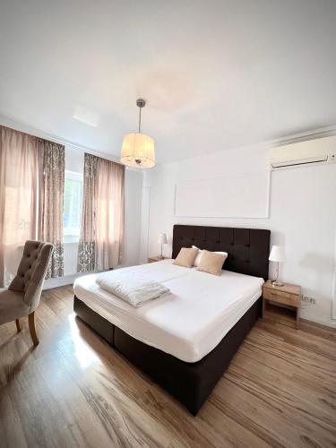 a bedroom with a large bed and a chair at Armonia Apartments in Timişoara