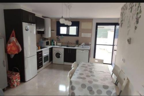 eine Küche mit einem Tisch und einem Kühlschrank sowie einem Tisch und Stühlen in der Unterkunft Piso planta baja y gran patio con piscina comunitaria de alquiler temporal in Daimús