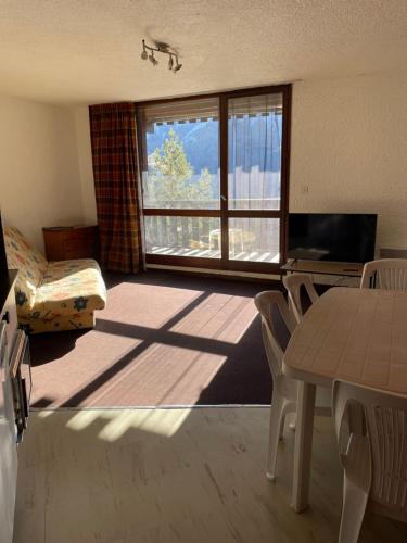 un salon avec une table et des chaises et une fenêtre dans l'établissement T2 Praloup 1500, à Uvernet