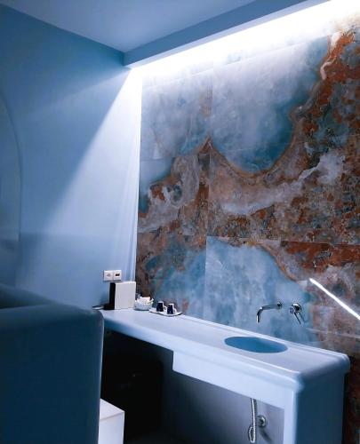 a bathroom with a sink and a stone wall at Mata's Apartments in Tinos Town