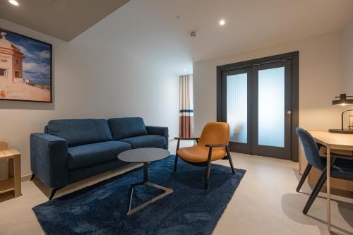 a living room with a blue couch and a table at Best Western Premier Malta in St Paul's Bay