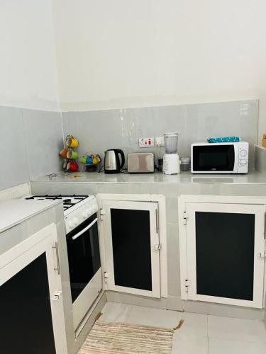 a kitchen with white cabinets and a stove top oven at Blossom House Zanzibar in Kitongani