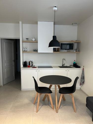 une cuisine avec une table, des chaises et un évier dans l'établissement Le petit appartement d’Arles, à Arles