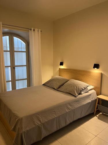 une chambre avec un grand lit et une fenêtre dans l'établissement Le petit appartement d’Arles, à Arles