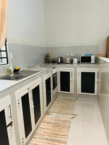 a kitchen with white cabinets and a counter top at Blossom House Zanzibar in Kitongani