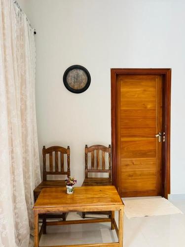 a wooden table with two chairs and a wooden door at Blossom House Zanzibar in Kitongani