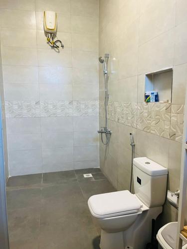 a bathroom with a toilet and a glass shower at Blossom House Zanzibar in Kitongani