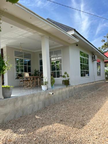 a white house with a porch with a patio at Blossom House Zanzibar in Kitongani