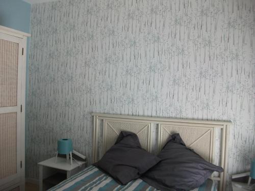 - un lit avec des oreillers dans une chambre avec du papier peint dans l'établissement Mathilde, à Lesparre-Médoc