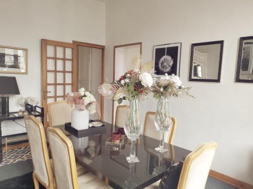 une salle à manger avec une table en verre et des fleurs. dans l'établissement Appartement spacieux Douai, à Douai