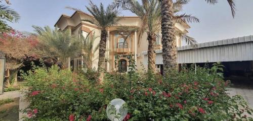 a house with palm trees and flowers in front of it at Fujairah Korean Guest House KUA in Fujairah