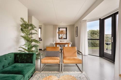 a living room with a green couch and chairs at Vakantiehuis aan het water -incl laadpaal- in Ewijk