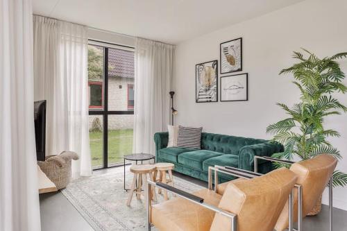 a living room with a green couch and a table at Vakantiehuis aan het water -incl laadpaal- in Ewijk