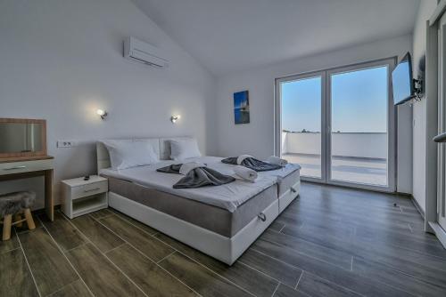 Un dormitorio blanco con una cama y una ventana grande. en Villa Joanna - hidden oasis with pool, gym & garrage, en Novalja