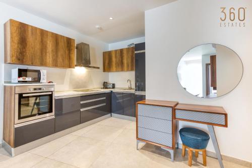 a kitchen with brown cabinets and a mirror at The Swieqi Poolside Suites in Is-Swieqi