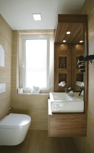 a bathroom with a toilet and a sink and a window at Hotel Römerhof in Leukerbad