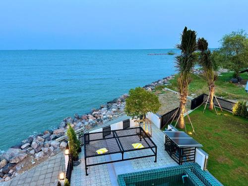a view of the ocean with a table and benches at Cape House in Ban Bang Kaeo