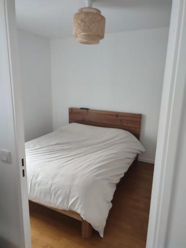 un lit avec des draps blancs et une tête de lit en bois dans l'établissement Prox Stade France appart 2P Chaleureux, à Saint-Denis