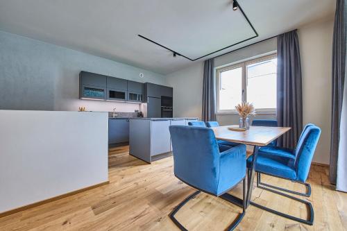 a kitchen and dining room with a table and blue chairs at sGmiatli – Dein Hideaway Apartment in Kappl