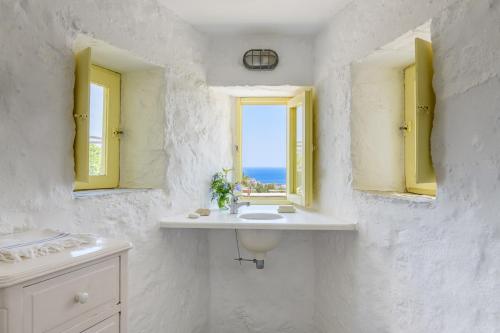 a white bathroom with a sink and a window at Amazing Sea View, Mykonos Cycladic Villa, Priv Pool in Mýkonos City
