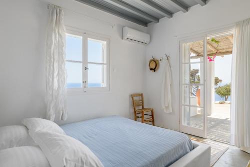 a white bedroom with a bed and a large window at Amazing Sea View, Mykonos Cycladic Villa, Priv Pool in Mýkonos City