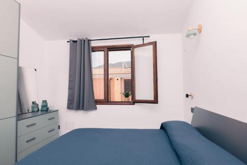 ムラヴェーラにあるAppartamento Le Margheriteの青いベッドと窓のある寝室