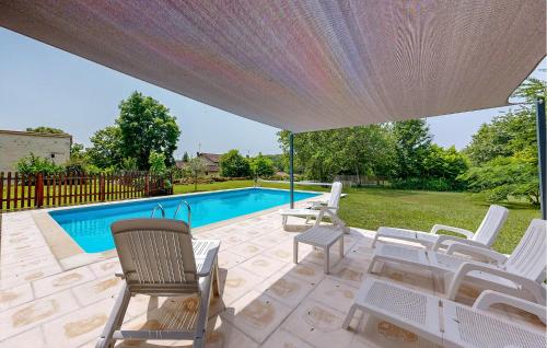 a patio with white chairs and a swimming pool at Nice Home In Mareuil En Perigord in Cercles