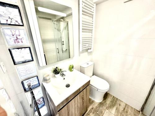a bathroom with a sink and a toilet and a mirror at Camín al Mar cudillero parking free sea views in Cudillero
