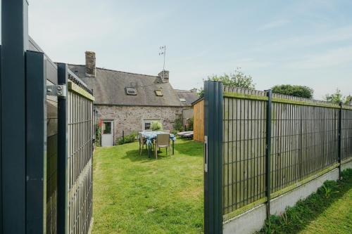 a fence in front of a yard with a table at Gite Les Dauphins à Matignon in Matignon