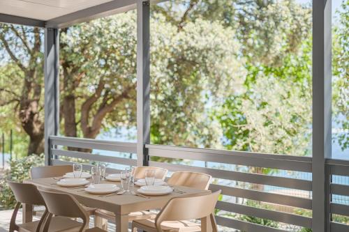 a table and chairs on a patio with a large window at Elements Camping Selce Mobile homes in Selce