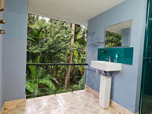 a bathroom with a sink and a large window at Travelers Guest House in Kundapur