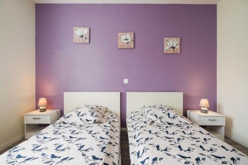 a bedroom with a bed and a purple wall at Kermat in Matignon