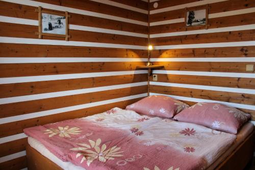 a wooden room with a bed with two pink pillows at Pension H in Jáchymov
