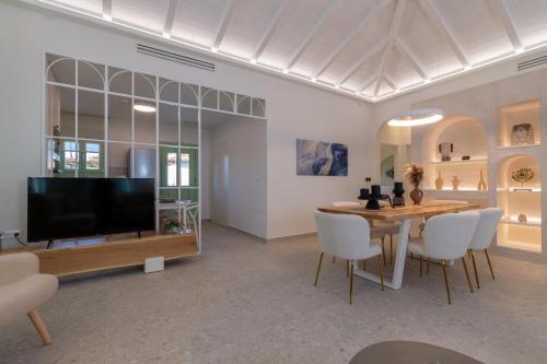a living room with a television and a table and chairs at Pnoe Luxury Villa in Ierissos
