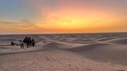 a group of people riding horses in the desert at Camp Dunes Insolites Sabria in Sabria