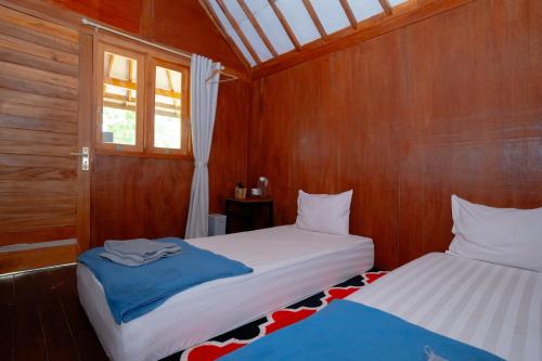 two beds in a room with wooden walls at RedDoorz Syariah near Lombok Epicentrum Mall in Mataram