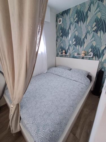 - un petit lit dans une chambre avec rideau dans l'établissement La chaumière en bord de mer, à Les Sables-dʼOlonne