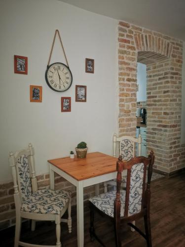 a dining room table with two chairs and a clock on the wall at Kúria Apartman Budapest with free parking in Budapest