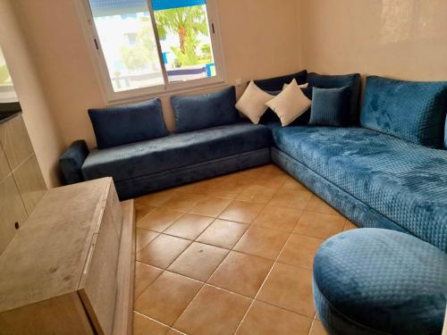 a living room with a blue couch and a window at Appartement Kabila Vista à 10min à pied de la plage in Marina Smir