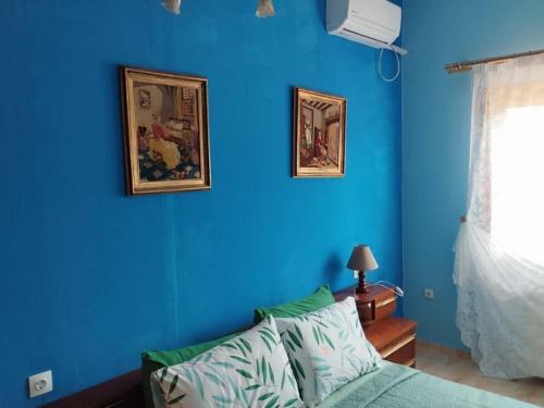 a blue room with a bed and two pictures on the wall at Η μαγική Εdem ένας μέρος χαλαρωσης in Grammatiko