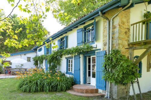 une vieille maison avec des volets bleus et des fleurs dans l'établissement Maison De Charme Avec Jacuzzi, à Arcangues
